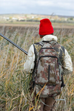 A hunter with a gun in camouflage clothing. A gentleman with a gun, medium shot, unrecognizable.