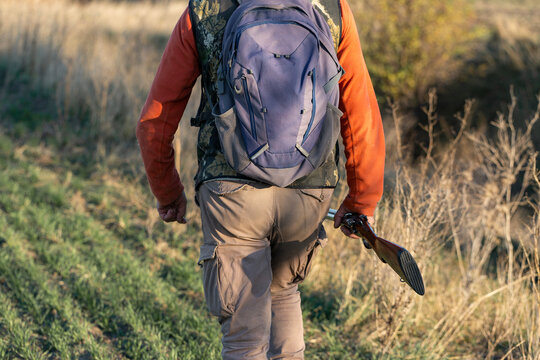 A hunter with a gun in camouflage clothing. A gentleman with a gun, medium shot, unrecognizable.