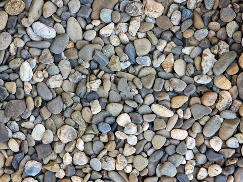 Pebble stone texture full frame background. Top view close up of smooth river or sea gravel pattern, natural grey stones backdrop for landscaping, spa, and exterior design.