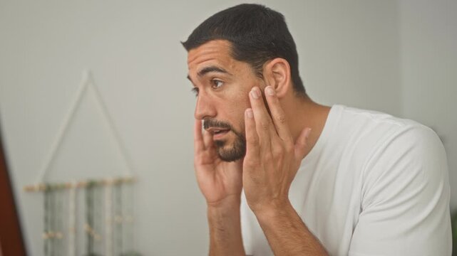 Man touching jawline and checking beard in a building mirror while performing skincare routine; self care serenity.
