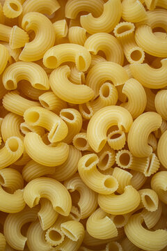 Chifferi rigati pasta texture full frame background. Top view close up of raw dry macaroni pattern, yellow italian elbow pasta ingredient for traditional cooking and culinary.