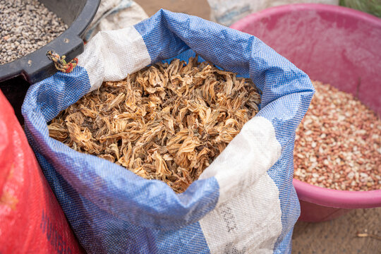 sac rempli de fleurs s&eacute;ch&eacute;es, plus pr&eacute;cis&eacute;ment des calices d'hibiscus (connus sous le nom de bissap en Afrique de l'Ouest, utilis&eacute;s pour la c&eacute;l&egrave;bre boisson locale)