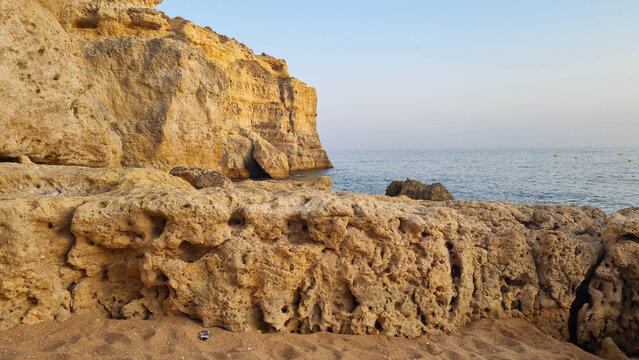 Weathered limestone cliffs with natural caves under clear blue sky on Mediterranean coast