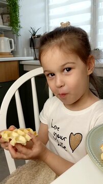 A beautiful young girl-child eats Belgian waffles with a happy face, smiles and laughs.