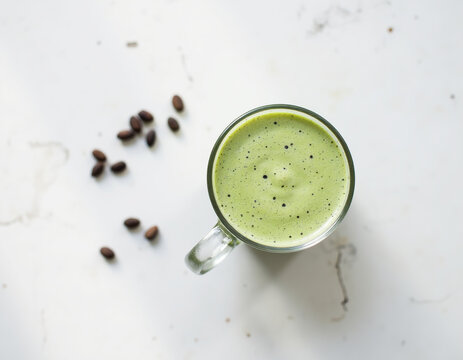 Top View Flat Lay of Iced Matcha Green Tea Latte Glass Decorated with Coffee Beans on White Marble