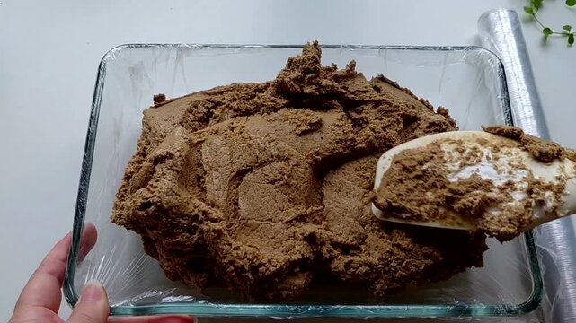 The man puts the halva into the mold with a spatula, preparing it. The process of making homemade halva. Sunflower halva.