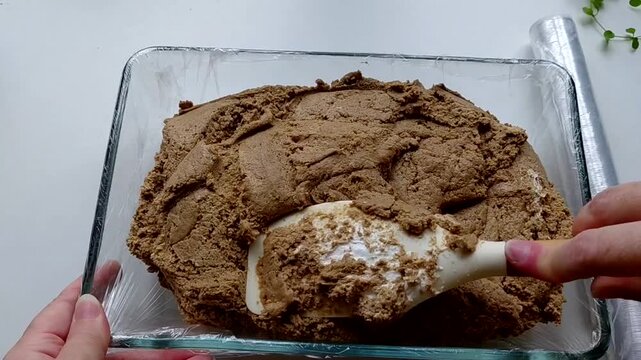 The man puts the halva into the mold with a spatula, preparing it. The process of making homemade halva. Sunflower halva.
