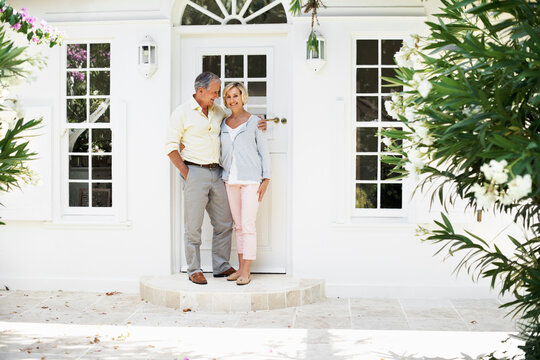 Senior, couple and hug at front door of new home for relocation, downsizing support or stability. Happy portrait, people and embrace outdoor for property purchase, comfortable retirement or milestone