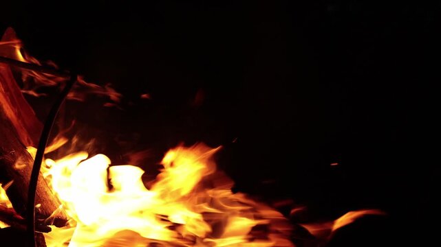 Close-up of vibrant orange flames dancing and flickering in the darkness