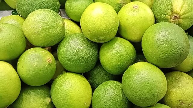 Pile of fresh green lemons and limes on market stall