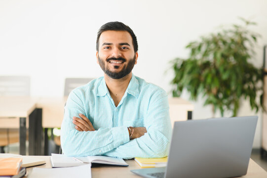 Indian student smiling working on laptop at university
