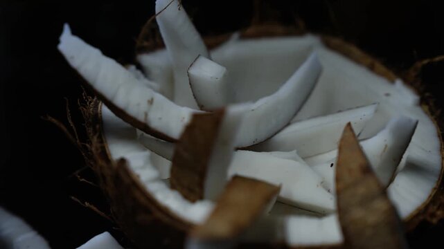 Close up of fresh coconut pieces in a half shell, Fresh coconut pieces in shell on dark background