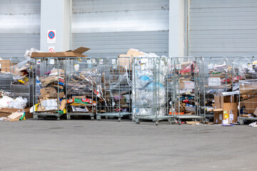 Collected cardboard and plastic packaging waste prepared for recycling behind a shopping mall