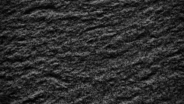 Close‑up of dark gray granite surface with natural wave‑like mineral patterns, coarse crystalline texture, and speckled details, creating an abstract stone background.