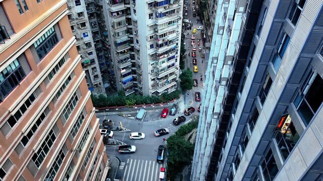 High angle shot of bustling traffic intersection between dense residential apartment buildings in Hong Kong city.
