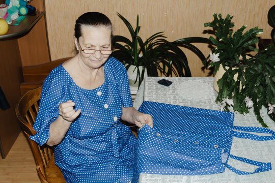 gentle grandmother blue top patiently shows her young grandson how sew piece fabric focused collaboration capturing warmth family learning passing traditions quiet joy creating something together