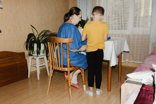 gentle grandmother blue top patiently shows her young grandson how sew piece fabric focused collaboration capturing warmth family learning passing traditions quiet joy creating something together
