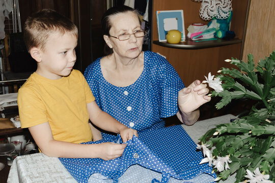 gentle grandmother blue top patiently shows her young grandson how sew piece fabric focused collaboration capturing warmth family learning passing traditions quiet joy creating something together
