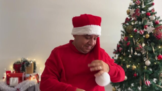 Hombre poni&eacute;ndose el gorro de Pap&aacute; Noel sonriendo