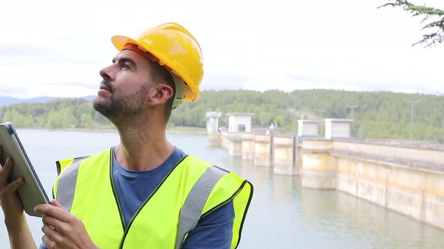 Hydroelectric Infrastructure Engineer Holding a Tablet and Writing Inspection Notes 