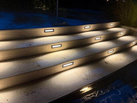 Modern Outdoor LED Step Lights Illuminating Exterior Concrete Stairs at Night Time, Contemporary Architectural Landscape Lighting Design for Safety and Decoration in Residential or Resort Patio