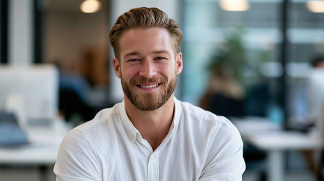 Portrait of attractive smiling man sitting in office and looking at camera in professional corporate setting, business confidence concept, corporate portrait photography, blurred