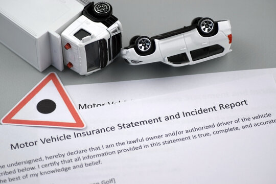 Car insurance policy document and toy cars on desk.