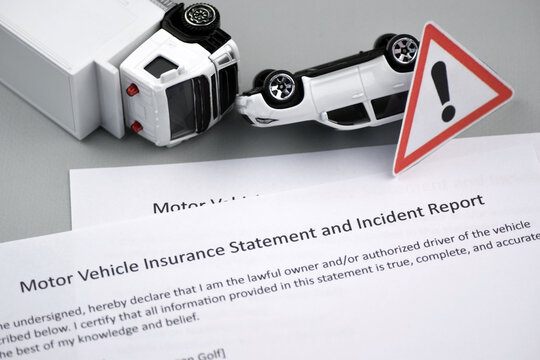 Car insurance policy document and toy cars on desk.