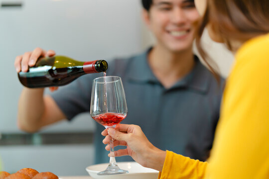 happy Asian couple drinking red wine together in kitchen room