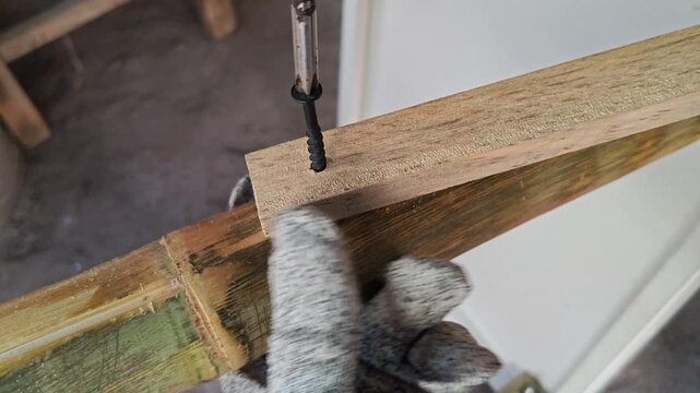 Person driving screw to join wood block and bamboo pole