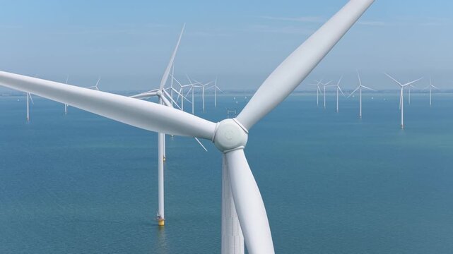 Aerial drone view of an offshore wind farm station in the sea. Modern renewable energy turbines generating clean electricity and sustainable alternative power in the ocean.