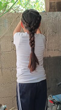 Young girl playing bouncing ball against outdoor house wall