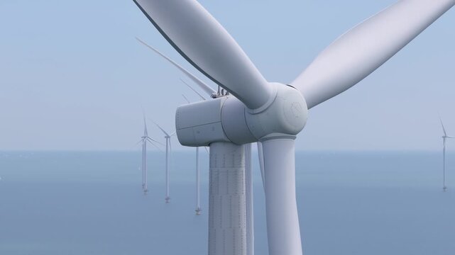Aerial drone view of an offshore wind farm station in the sea. Modern renewable energy turbines generating clean electricity and sustainable alternative power in the ocean.