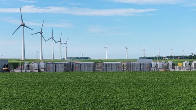 Aerial view on battery energy storage system for renewable power plant and wind turbines. Industrial lithium batteries facility for clean electricity grid management and sustainable infrastructure.