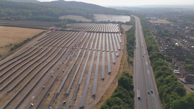 Aerial view of a near completed large scale solar farm on the outskirts of Telford in the UK with the M54 motorway running alongside as the sun goes down on an evening