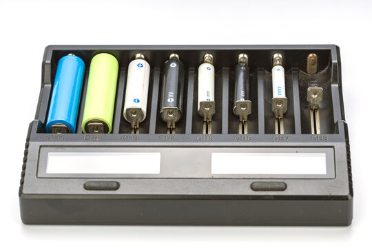 Assorted rechargeable and disposable battery sizes AA AAA AAAA alkaline and blue green 18650 lithium ion cells placed together in slots CH1 through CH8 of universal smart charger device