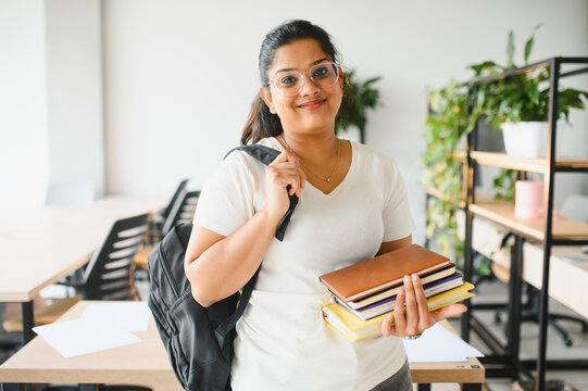 Indian female student smiling, carrying books and backpack