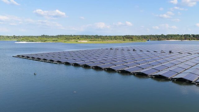 Aerial drone view of a floating solar panel farm on a calm lake surface. Modern green technology facility producing clean renewable energy on water.