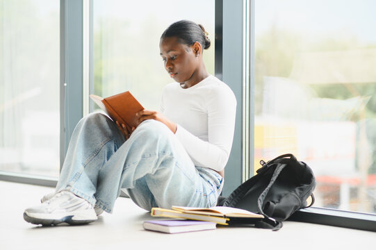 African american female student studying book at university