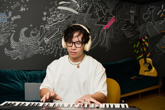 Young Asian man creates music in a vibrant recording studio filled with creative energy