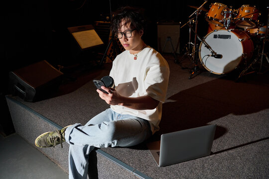 Young Asian man creates music magic in a cozy recording studio setting during a vibrant session