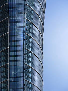 Curved glass facade of a modern office tower, representing contemporary corporate architecture, commercial real estate and urban development.