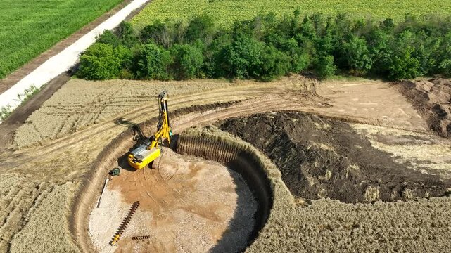 Aerial View of a Drilling Rig Excavating a Wind Turbine Foundation in a Wheat Field. Renewable Energy Infrastructure in Farmland.