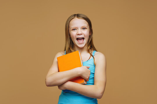 A happy schoolgirl with a books stands on an isolated background. Back to school and joy of learning concept.