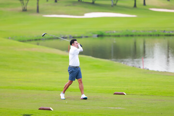 Obraz premium professional golfer on field. Asian Man Golfer Hitting Golf Shot on golf Course. teeing off golf ball. Sport outdoor