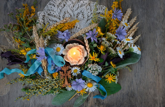 Herbs, flowers tied to sacred bouquet, cross and candle on table close up. Herbal consecration - traditional customs on August 15, Assumption of Mary day. christian religion festive ritual. top view