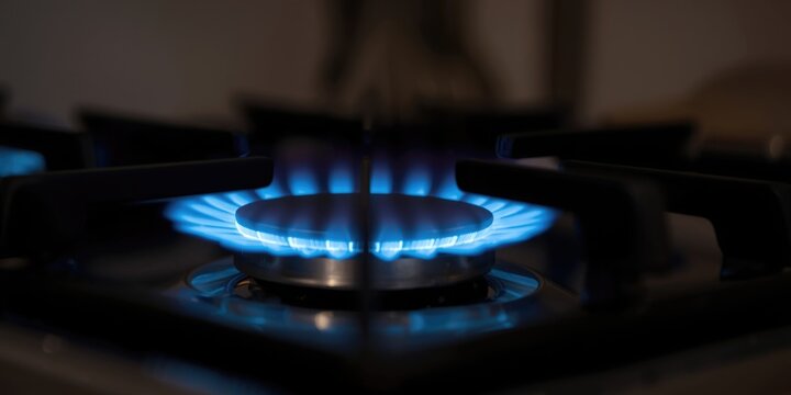 Blue Gas Flame Burning on a Modern Kitchen Stove with Dark Background