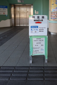 Signboard indicating the 20-yen fee for pushing bicycles and the toll box at the entrance of the Kanmon Pedestrian Tunnel in Shimonoseki, Japan, May 13, 2026
