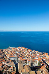 Fototapeta premium Aerial view of the coastal town of Cefalu in Sicily, Italy, showcasing its dense urban landscape and the vast Mediterranean Sea
