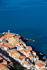 Fototapeta premium Aerial view of the coastal town of Cefalu in Sicily, Italy, showcasing its dense urban landscape and the vast Mediterranean Sea